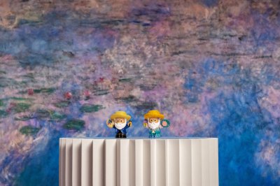 Two small statuettes of Claude Monet sit on a pedestal in front of Monet's 