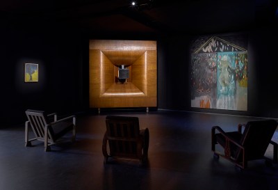 Several chairs were placed in front of large speakers and a painting shaped like a house.
