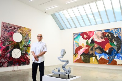 A man stands next to an abstract painting.