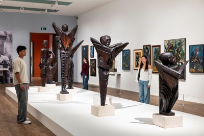 There are several life-size sculptures of figures, and many paintings hang on the walls.