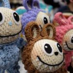 A group of smiling crochet dolls with big, sharp teeth.