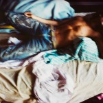 Still images from the video show a shirtless man wearing jeans lying on a messy bed.