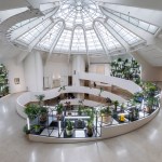 A ramp surrounds the inner atrium, whose inner walls have a grid-like structure with plants.
