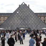 A group of people in front of the glass pyramid.