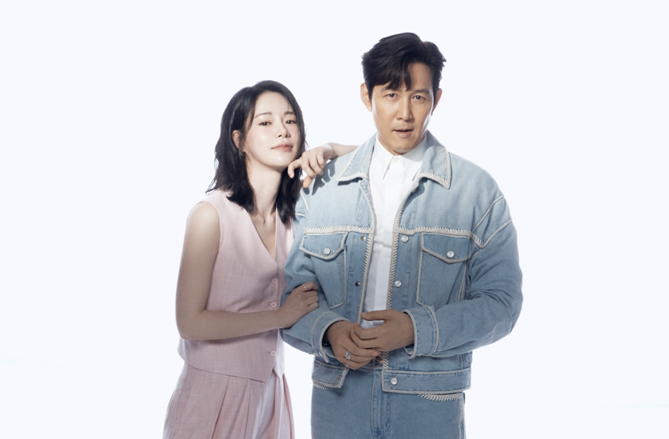 A woman in a pink suit leans on the shoulders of a man in denim.