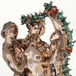 Detailed shot of a shiny sculpture of three ladies and some garlands.