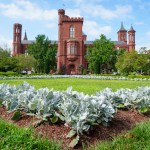 A brick castle-like building in front of a grassy garden.