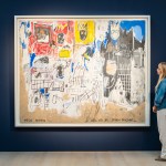 A woman stands next to a painting.