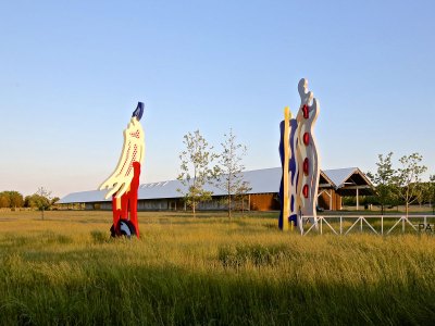 Two abstract sculptures resembling brush strokes stand in the open space in front of the museum building.