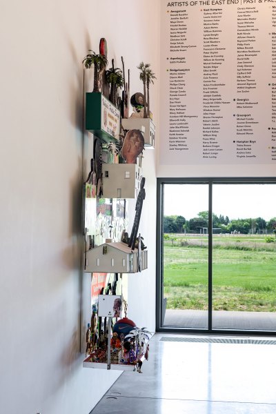 Side view of the wall-mounted work, a sculpture in which buildings and figures suddenly appear.