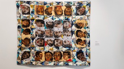 A quilt featuring the painted heads of Black men and women pointed in various directions.