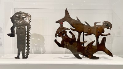 Two metal sculptures of smiling figures.