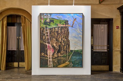 One photo shows a large painting of a woman preparing to dive from a flaming diving board, with a grassy lawn in front of a steep rocky cliff face. This photo hangs on the white wall of the hotel living room.
