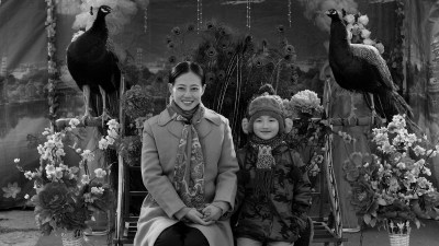 A black and white image of a woman and a child is placed between two birds and two vases filled with flowers.
