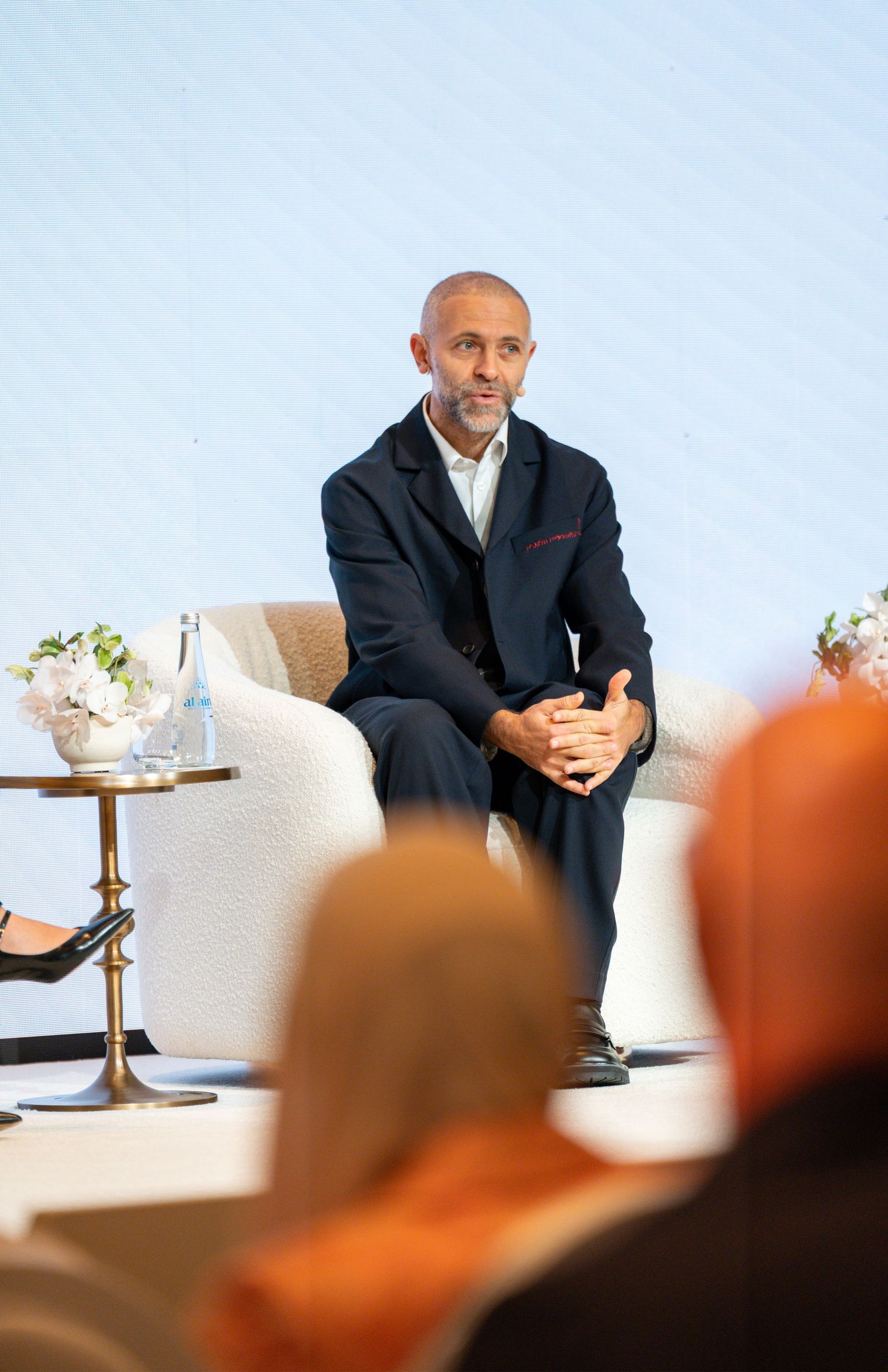 Image may include a person sitting Blazer Clothing Outerwear Jackets Adults Footwear and Shoes