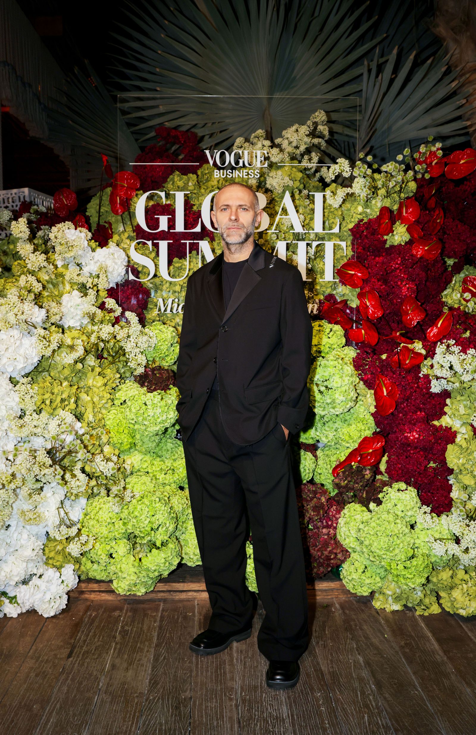 Image may contain standing people, adult clothing, formal wear, suits, faces, head photography, portraits and flowers