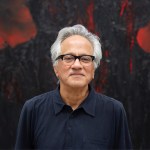 Portrait of a brown man with glasses and gray hair.