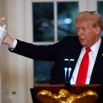 U.S. President Donald Trump holds a model of the Arch during a speech during a ballroom fundraising dinner in the East Room of the White House in Washington, DC, on October 15, 2025.