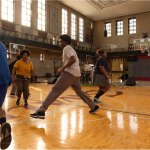 Photo of young black adults on a basketball court who appear to be performing a dance.