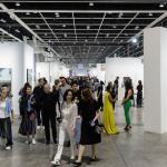 A group of people walk through the aisles of an art fair.