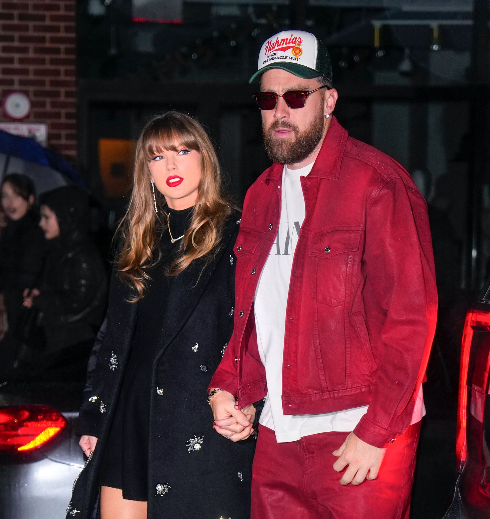 Image may contain Travis Kelce Taylor Swift adult clothing, coats, jackets, hats, body parts, hands and photobombing