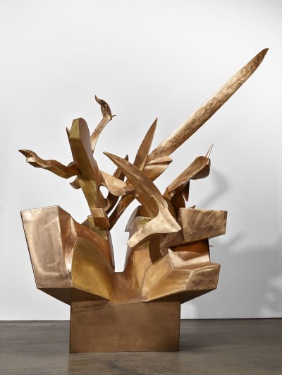 Polished bronze abstract sculptures of various shapes protrude from the base.