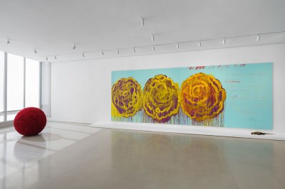 Installation view of the art gallery, with a large painting hanging on the wall and a round red sculpture on the left.