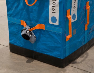 A sock with an image of Edgar Allan Poe printed on it is tied to the handle of a plastic bin.