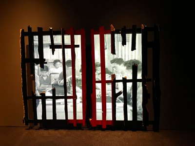 A video sculpture showing a broken wooden fence behind which, across two screens, plays propaganda footage of Japanese Americans in internment camps.