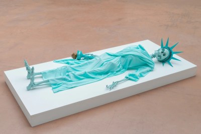 A sculpture composed of a blue skeleton with a Statue of Liberty's foam crown.