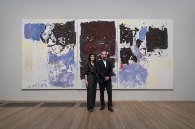 A woman and a man in front of a large abstract painting.