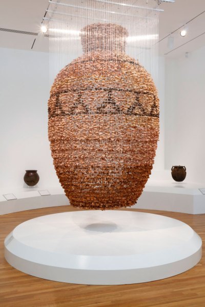 A hanging installation of large vessels made from hundreds of terracotta leaves, all suspended from the ceiling.