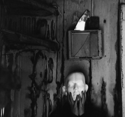 A photo of a person wearing a white mask in an abandoned environment.