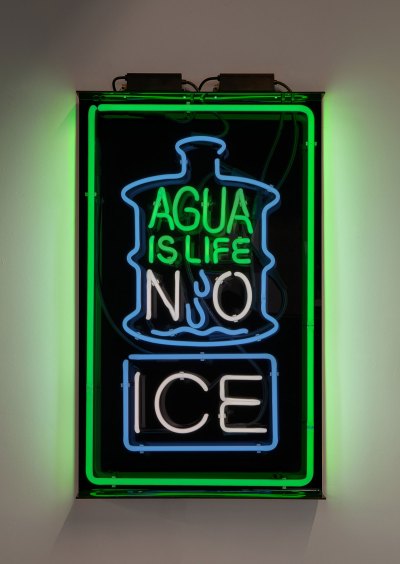 A neon sculpture that says 'AGUA IS LIFE NO ICE' with a drawing of a large water jug.