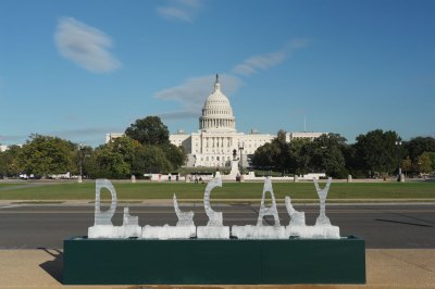 An ice sculpture that spelled 'DEMOCRACY' that has mostly melted with the White House seen in the background.