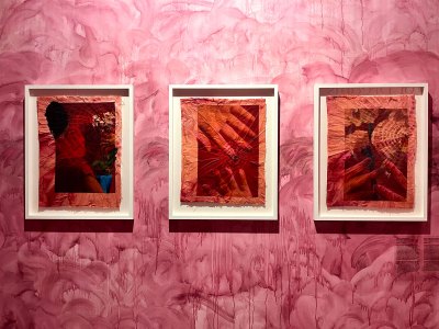 Three hand-dyed works on a museum wall that has been dripped with pinkish dye. 