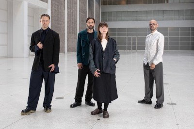 Four people standing in a gray atrium.