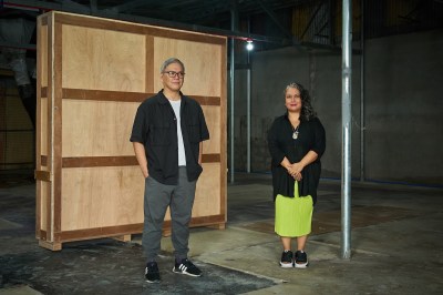 Portrait of Jon Cuyson and Mara Gladstone in front of a crate.