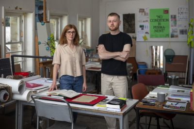 A man and a woman standing at a table lined with books.