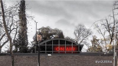 A building with a glowing 'ON AIR' symbol visible through its roof.