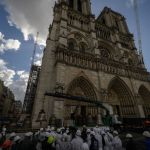 A huge stone cathedral stands against the blue sky and white clouds.