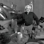 A man stands with one arm on an architectural model.