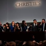 A group of people in suits and gowns were all talking on the phone. Underneath the booth was a glowing sign that read 