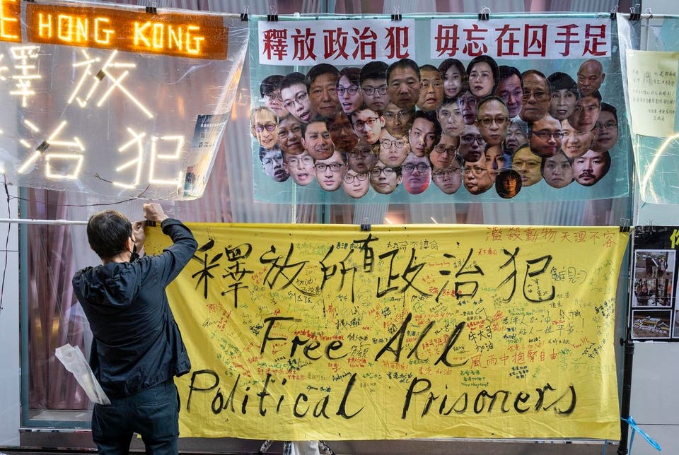 A pro-democracy activist hangs a yellow banner that reads...