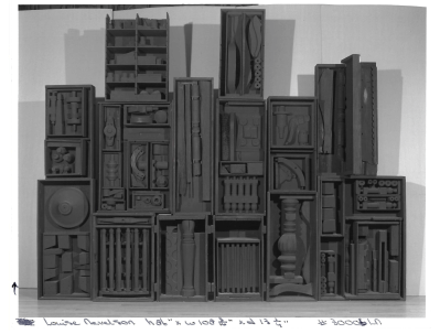 A sculpture comprised of many black boxes with black things inside them.