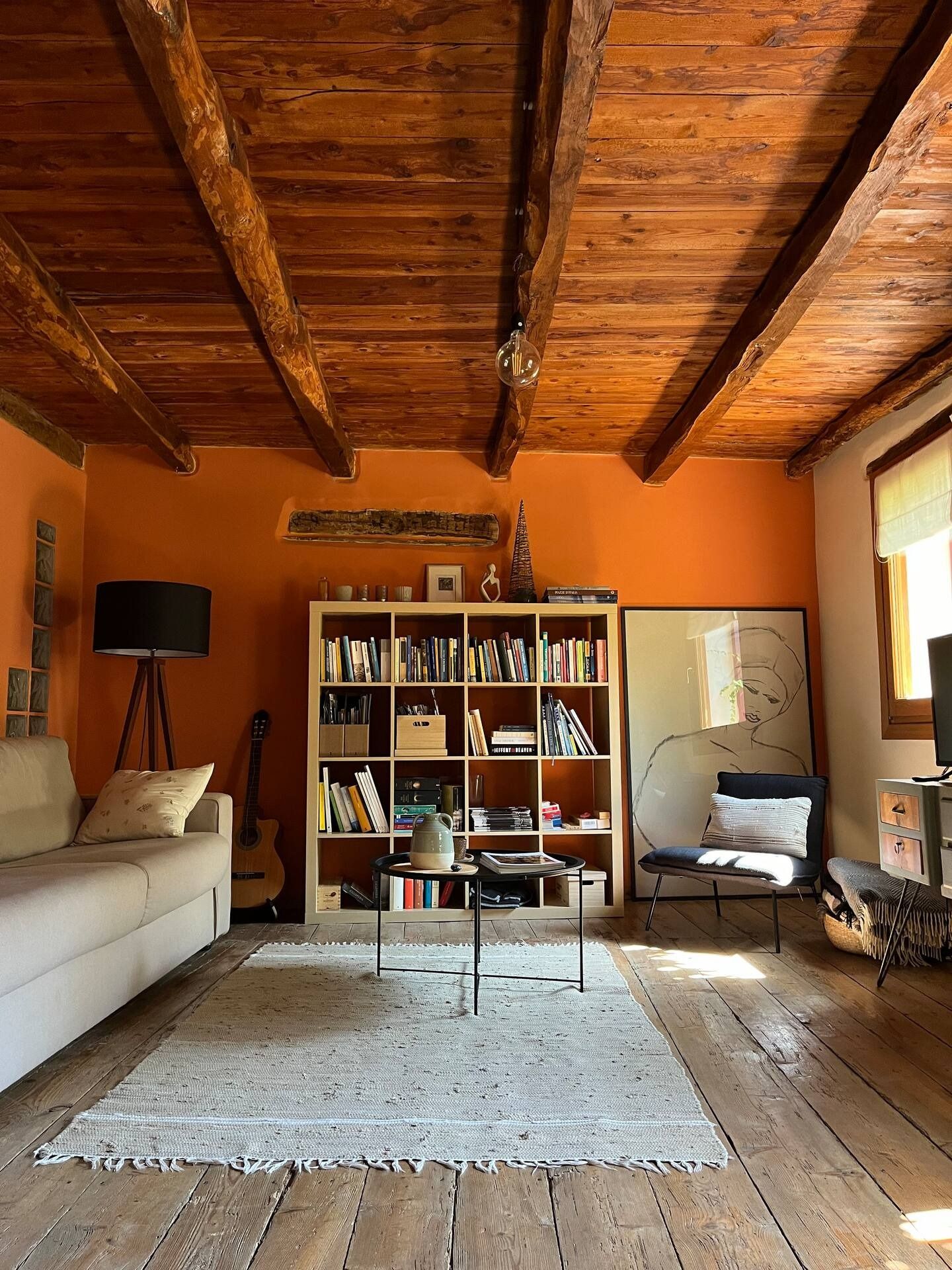 Image may contain interior interior design, wood, hardwood, stained wood home decor, rug, sofa, furniture and guitar