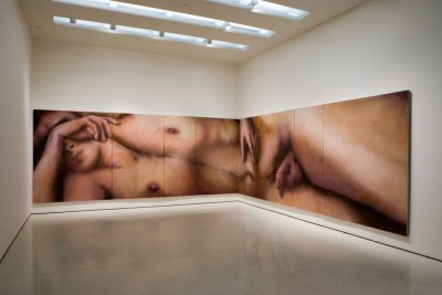 A large-scale painting that is installed along two walls of a museum, showing a fully naked man.