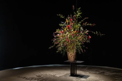 A towering sculpture of flowers in a vase on a black table.