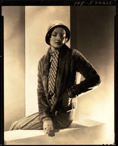 A woman in a skirt and scarf sits on the balcony.