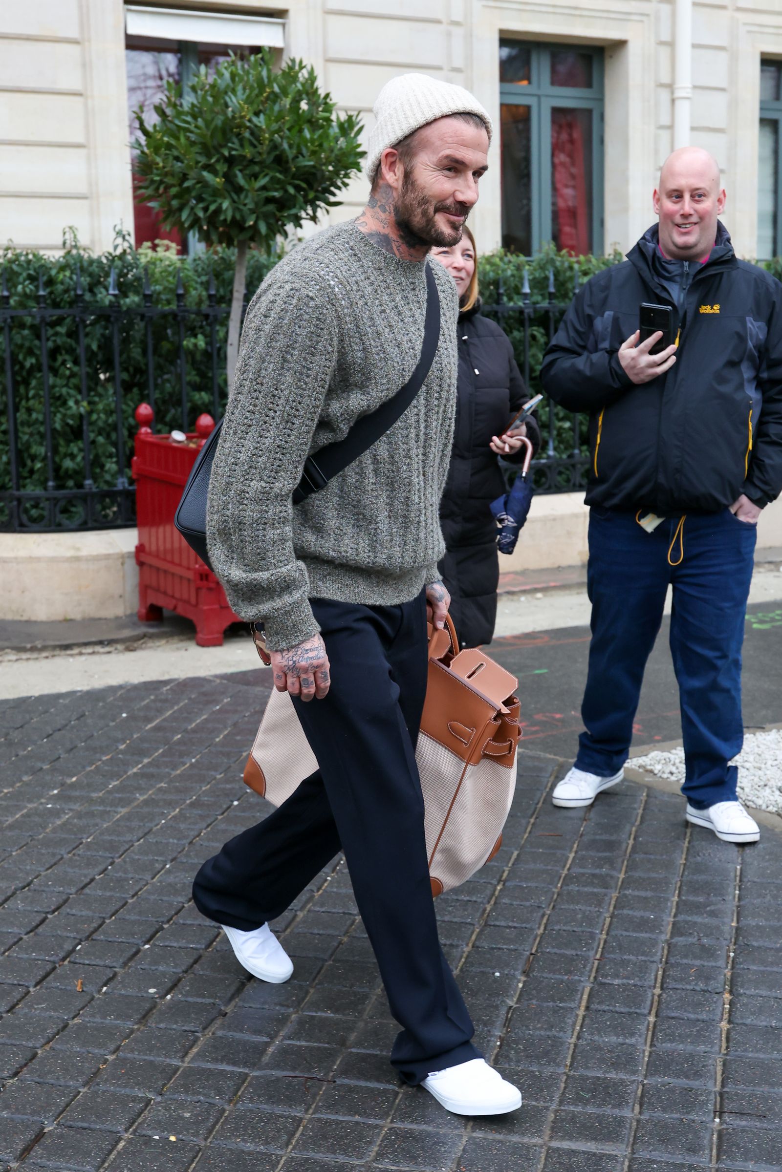 Image may contain David Beckham pedestrian adult walking, clothing, pants, accessories, bag, tote and head
